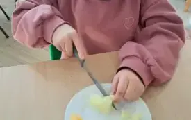 dziewczynka kroi owoce na talerzyku