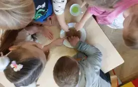 dzieci stoją dookoła talerza z wodą i pieprzem i dotykają wody paluszkami z mydłem