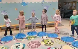 dzieci stoją przy niebieskich kołach wykonanych z folii przed kt&oacute;rymi leżą kolorowe kijki