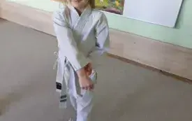 dziewczynka ubrana w kimono prezentuje pozę karate