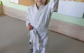dziewczynka ubrana w kimono prezentuje pozę karate