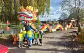dzieci wraz z panią pozują do zdjęcia w tle dekoracja w kształcie ogromnego kolorowego chińskiego smoka 