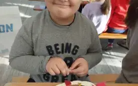 chłopiec uśmiecha się do zdjęcia przed nim na stole leży szablon dyni z napisem dobronianka i stoją w pudełku nożyczki