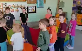 dzieci trzymają dookoła kolorową chustę klanza