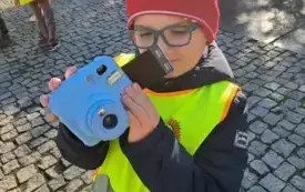 chłopiec w kamizelce odblaskowej trzyma aparat i patrzy na zdjęcie 