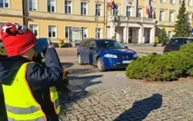 chłopiec w kamizelce odblaskowej robi zdjęcie w tle widać Urząd Miasta Zgierza