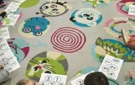 dzieci siedzą w kole przed nimi znajdują się karteczki z cyframi