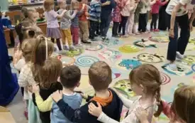 dzieci stoją w rzędzie z rękami na ramionach koleg&oacute;w z przodu wewnątrz koła pani
