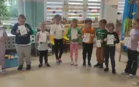 dzieci stoją w kole i trzymają kartki z r&oacute;żnymi cyframi