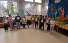 dzieci stoją w kole i trzymają kartki z r&oacute;żnymi cyframi