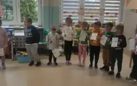 dzieci stoją w kole trzymają kartki z numerami