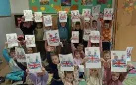 dzieci pozują do zdjęcia trzymając w g&oacute;rze karty pracy z widoczną flagą Wielkiej Brytani