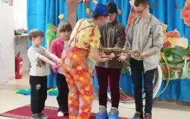 czworo dzieci trzyma węża na rękach przed nimi pani asekuruje zwierzaka