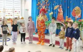 pani w kolorowym ubraniu i peruce wraz z dziećmi stoją w p&oacute;łkolu pani m&oacute;wi coś do mikrofonu