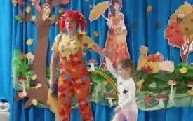 pani w kolorowym ubraniu i peruce obok niej stoi dziewczynka pani unosi jej rękę do g&oacute;ry