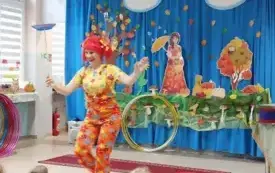 pani w kolorowym ubraniu i peruce prezentuje talerzyk na drążku