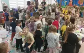 dużo dzieci stoi na sali dzieci trzymają maskotki