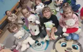 dziewczynki siedzą na dywanie i trzymają maskotki misie