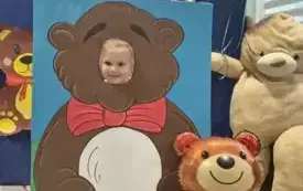 dziecko pozuje do zdjęcia w fotobudce miś widać dużą sylwetkę misia i buzię dziecka obok dekoracja miś balon