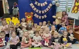 grupa dzieci wraz z panią nauczycielką pozują do zdjęcia w tle dekoracja dzień pluszowego misia