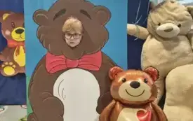 dziecko pozuje do zdjęcia w fotobudce miś widać dużą sylwetkę misia i buzię dziecka obok dekoracja miś balon