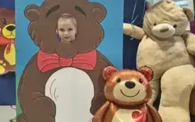 dziecko pozuje do zdjęcia w fotobudce miś widać dużą sylwetkę misia i buzię dziecka obok dekoracja miś balon