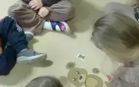 dziewczynki w małym kole siedzą na dywanie i układają sylwetę misia z element&oacute;w