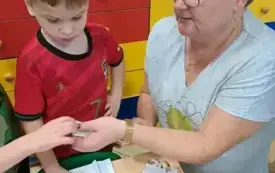 chłopiec pochylony nad kopertą leżącą na stoliku obok pani 