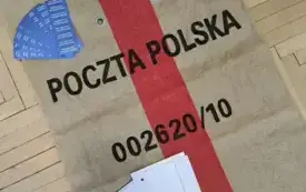 worek pocztowy z napisem poczta polska na nim leżą znaczki, naklejki i druki