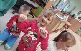 na pierwszym planie dziewczynka pokazująca linę na kt&oacute;rej widać węzeł