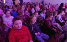 dzieci siedzą na krzesłach w chłodnym r&oacute;żowo fioletowym świetle