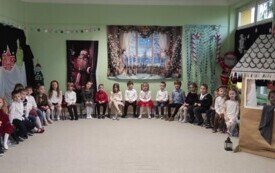dzieci siedzą na krzesełkach w p&oacute;łkolu za nimi i dookoła świąteczna i zimowa dekoracja
