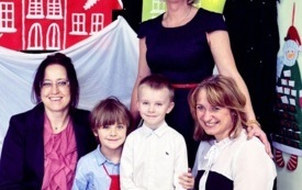 dwoje dzieci i trzy panie pozują do zdjęcia na tle kolorowych domk&oacute;w