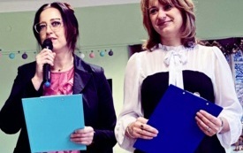 dwie panie z niebieskimi tabliczkami jedna pani trzyma mikrofon