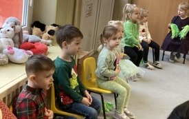 kilkoro dzieci siedzi na krzesełkach obok siebie