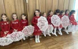 dziewczynki w czerwonych sukienkach z białymi koronkowymi parasolkami siedzą na ławeczce obok siebie