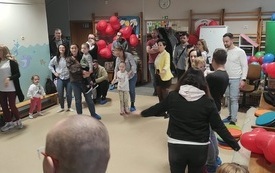 dzieci wraz z rodzicami oraz nauczycielki podczas zabaw w kole w środku pani przebrana za ogromną żabę