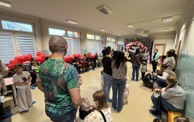 rodzice z dziećmi stoją w sali udekorowanej balonami orzed nimi panie nauvzycielki i pani dyrektor