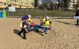 czworo dzieci w kamizelkach odblaskowych siedzi na karuzeli