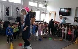 dzieci ustawione w rzedzie pokonują tor sensoryczny wśr&oacute;d dzieci stoją trzy panie