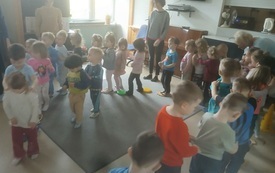 grupa dzieci ustawiona w rzędzie przechodzi po torze sensorycznym wśr&oacute;d nich panie