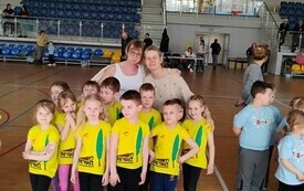 dzieci w koszulkach z logo przedszkola pozują do zdjęcia grupowego wraz z paniami