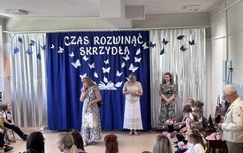 trzy panie stoją na środku sali w tle dekoracja na zakończenie roku