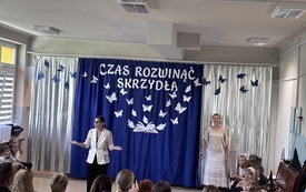 pani dyrektor Monika stoi na środku sali w tle dekoracja na zakończenie roku przedszkolnego