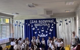 dzieci w programie artystycznym w tle dekoracja z motylkami czas rozwinąć skrzydła obok stoi pani