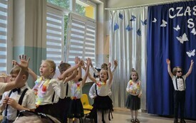 grupa dzieci w programie artystycznym stoi z uniesionymi rękami
