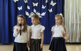 trzy dziewczynki stoją obok siebie jedna z nich trzyma mikrofon w tle dekoracja na zakończenie roku