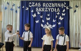 czw&oacute;rka odświętnie ubranych przedszkolak&oacute;w stoi obok siebie w tle dekoracja Czas rozwinąć skrzydła 