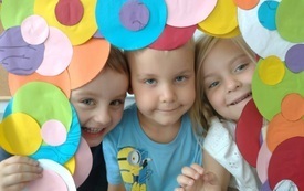 troje dzieci pozuje do zdjęcia w fotoramce z kolorowych k&oacute;łek