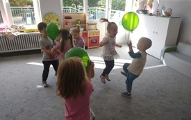 dzieci w parach trzymają lub podrzucają balony